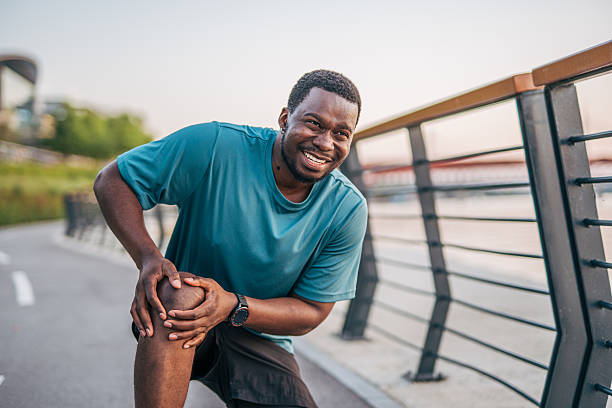 istock Young black man experiencing knee pain while jogging outdoors 2231079442