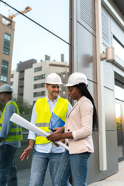 istock Two diverse Construction manager and architect reviewing blueprints on site outside office building 2231080307