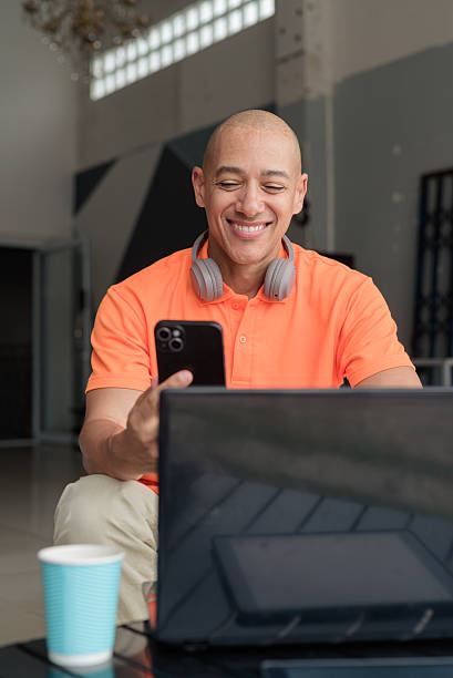 istock Bald Hispanic man sitting and using laptop computer and phone in coffee shop restaurant 2231084692