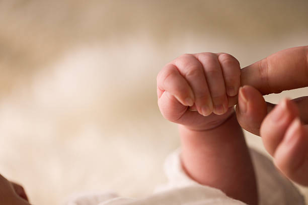 Close-up of mother's hand holding newborn baby's hand