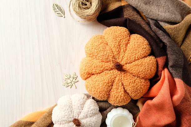 istock Rustic fall flat lay with plush pumpkins on a cozy autumn blanket with twine, wooden leaf cutouts, and candle. 2231093618