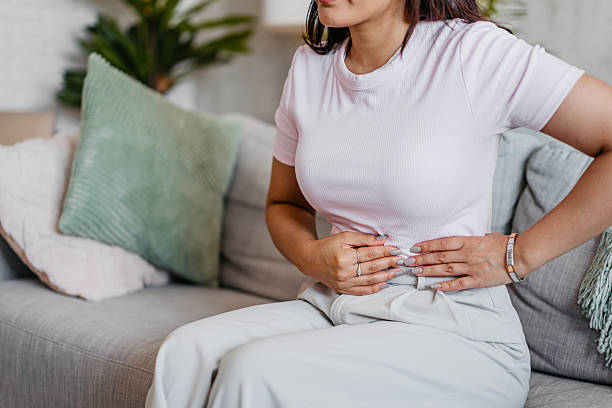 istock Young Indian Woman Having A Stomachache While Sitting On The Sofa At Home 2231096366