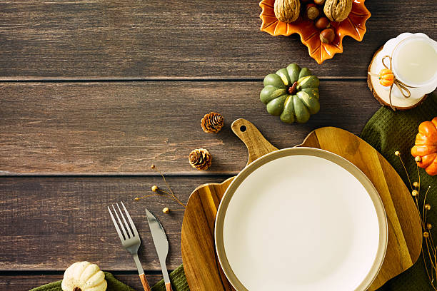 istock Autumn table setting with a empty plate, cutlery, and decorative pumpkins on a textured wooden background 2231096378