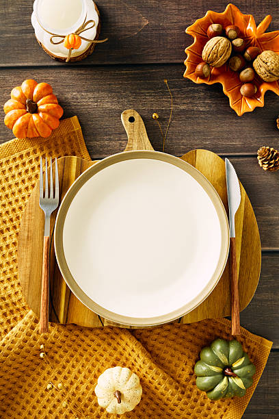 istock Autumn table setting with empty plate with cutlery, pumpkins, dried flowers, candle, acorns, walnuts. Thanksgiving, seasonal dining, fall holiday celebration concept. 2231096416