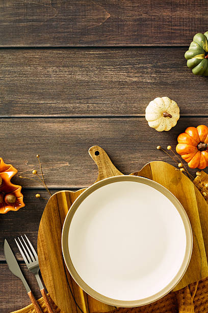 istock Autumn table setting with empty plate, vintage knife and fork, pumpkins, acorns, and dry flowers. Perfect for fall celebrations, Thanksgiving dinner concept 2231096509