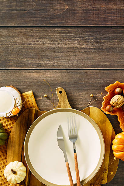 istock Top view of autumn table setting. Empty plate with cutlery, pumpkin, candle, acorns on a rustic wooden background. Ideal for fall themes, Thanksgiving 2231096625