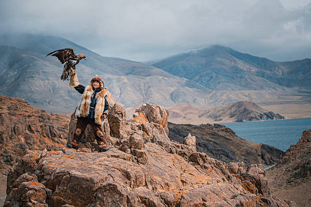 istock Traditional Mongolian Eagle Hunter Standing with Golden Eagle on Rocky Mountain Landscape 2231096792