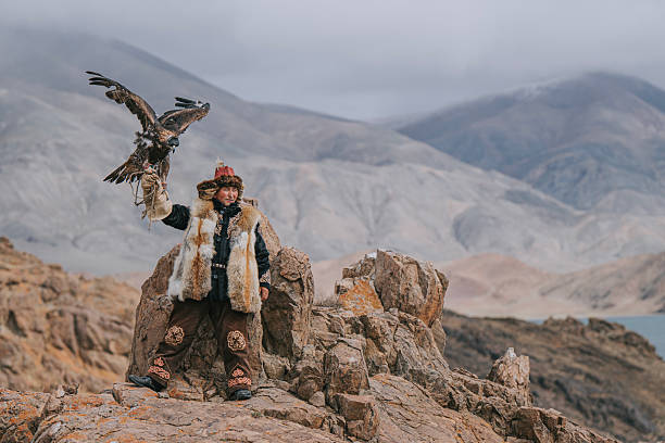 istock Traditional Mongolian Eagle Hunter Standing with Golden Eagle on Rocky Mountain Landscape 2231096802