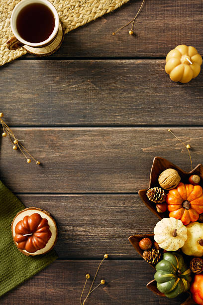 istock Autumn fall vertical background with decorative pumpkins, candles, pine cones, mug of tea on wooden table. Top view, flat lay. 2231096948