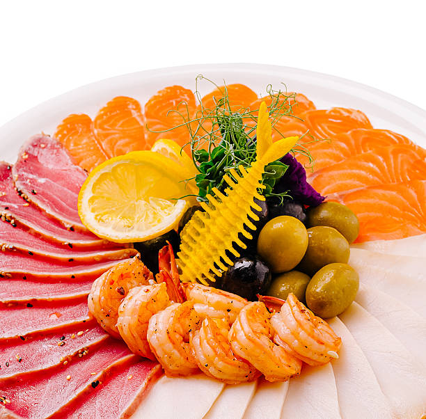 A colorful seafood platter showcases fresh shrimp, salmon, and tuna, garnished with olives and vibrant herbs. It offers a delightful array of flavors and textures for seafood lovers.