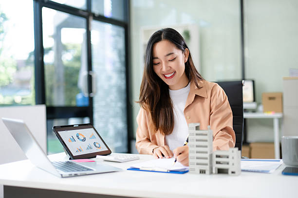 istock Confident Asian businesswoman smiling while presenting a modern building model in office 2231100282
