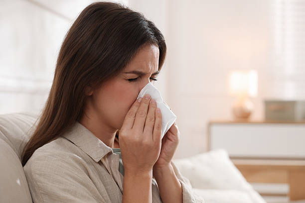 istock Young woman with tissue blowing runny nose at home 2231103199