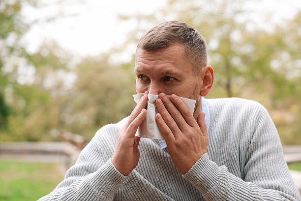 istock Man with tissue blowing runny nose in park 2231103206