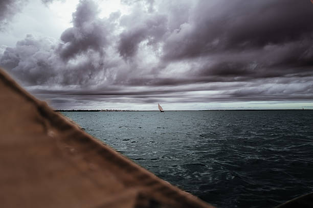 istock Fisherman boat sail on rainy day with deep clouds and a dhow boat far away 2231103509