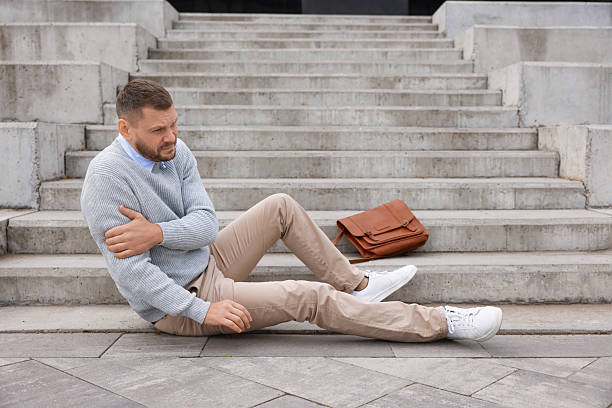 istock Man with injured arm on stairs outdoors after fall. Dangerous accident 2231103514
