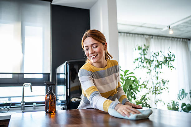 istock Smiling woman cleaning wooden table in modern kitchen 2231106284