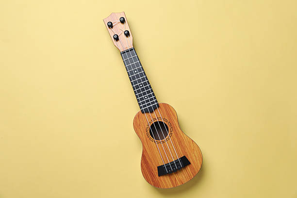istock One ukulele on pale yellow background, top view 2231108028