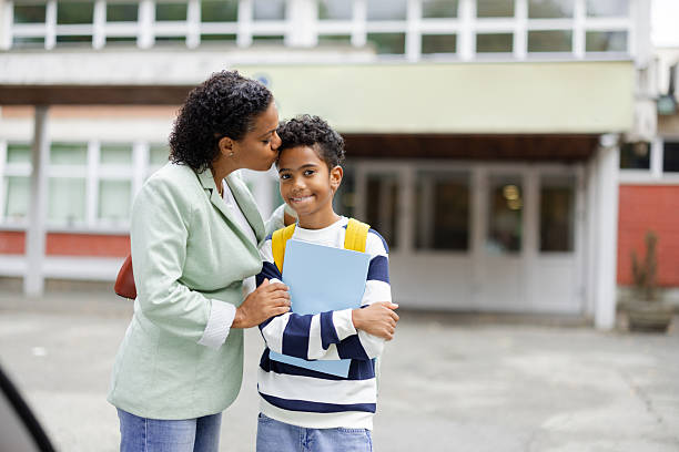 Mother is kissing her son on the forehead before he goes to school