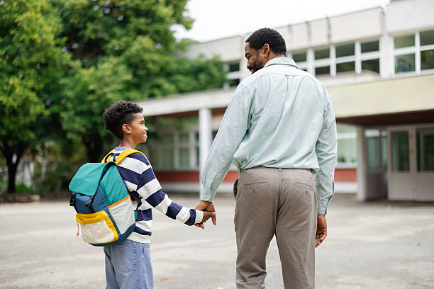 istock Father holding son's hand while walking to school 2231110884