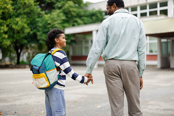 istock Father holding son's hand while walking to school 2231111077