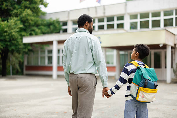 istock Father holding son's hand while walking to school 2231111086