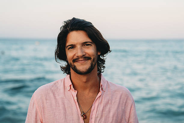 istock Young man smiling at the beach during sunset 2231112041