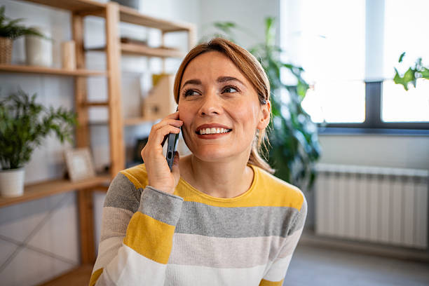 istock Smiling woman talking on mobile phone at home office 2231115105