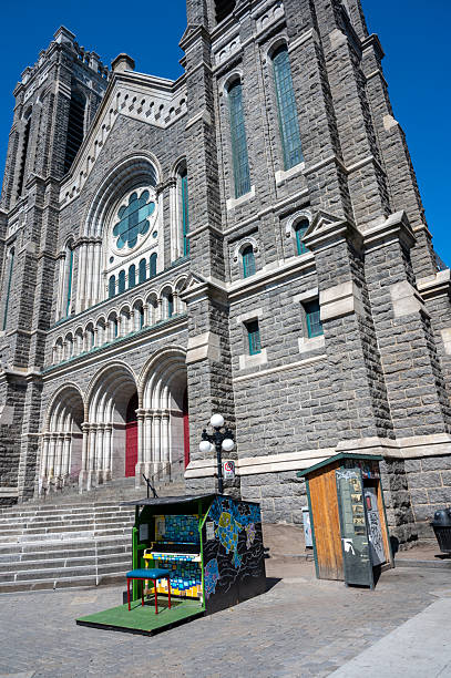 Public piano and sharing fridge on the sidewalk besides a catholic church downtown Quebec city during a summer day