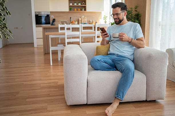 istock Young man relaxing on sofa, enjoying coffee and browsing smartphone at home 2231122002