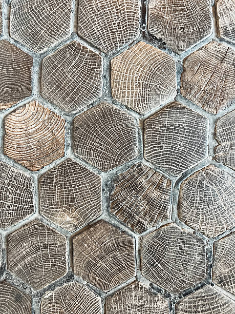 Close-up abstract shot of a textured wood surface made up of hexagonal shaped wooden tiles. Each tile features different grain patterns, creating areas of light and dark.