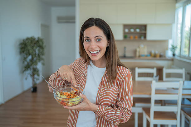 istock Young woman enjoying fresh salad in modern kitchen 2231125484