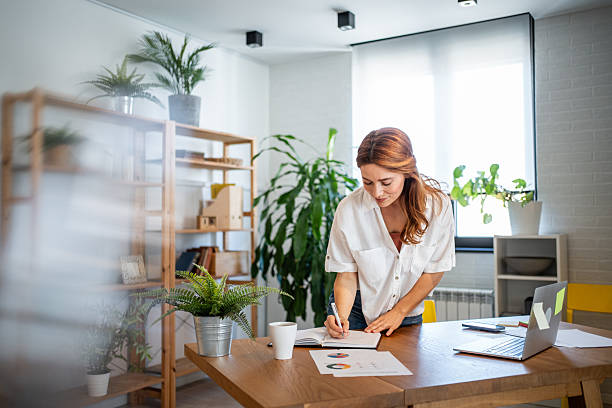 istock Young businesswoman working from home writing notes on a notebook 2231129700