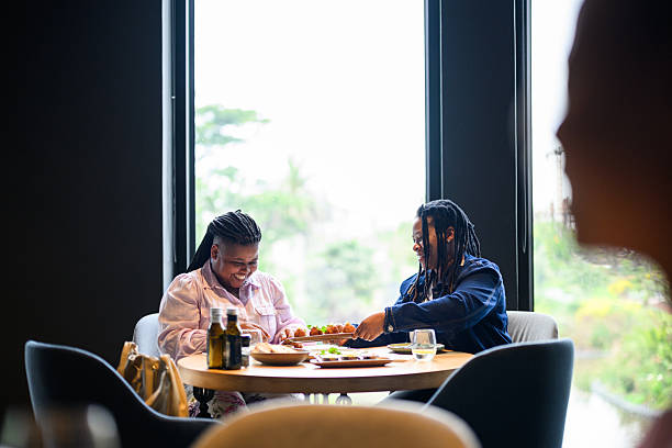istock Happy lesbian couple laughing and enjoying gourmet appetisers while dining at a modern restaurant table 2231131221