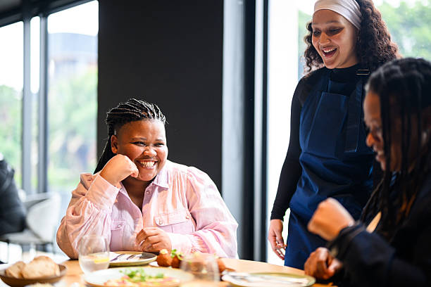 istock Black lesbian couple smiling while waitress serves them at a luxury restaurant table near large windows 2231131389