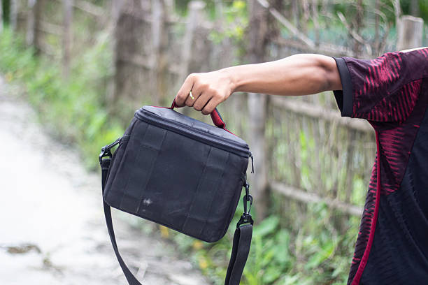 istock A persons hand carries a black camera bag with a shoulder strap outdoors 2231131466