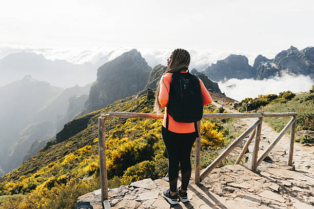 Young woman with a backpacking enjoying the view from a hiking trail overlooking a mountain range.