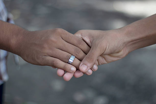 two hands clasped together, with one person wearing a silver ring, symbolizing unity, love, and a strong connection between them.