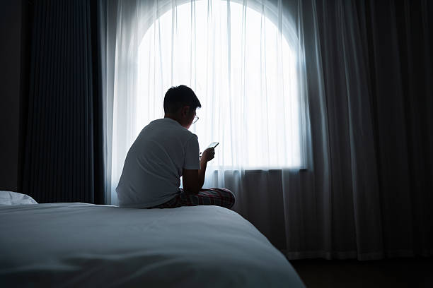 istock Teenager boy sitting on bed using mobile phone 2231134882