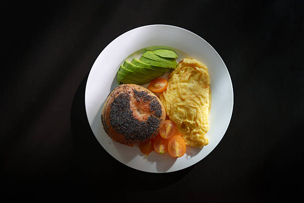 Top View of Breakfast Plate with Bagel, Avocado, Omelette, and Tomatoes
