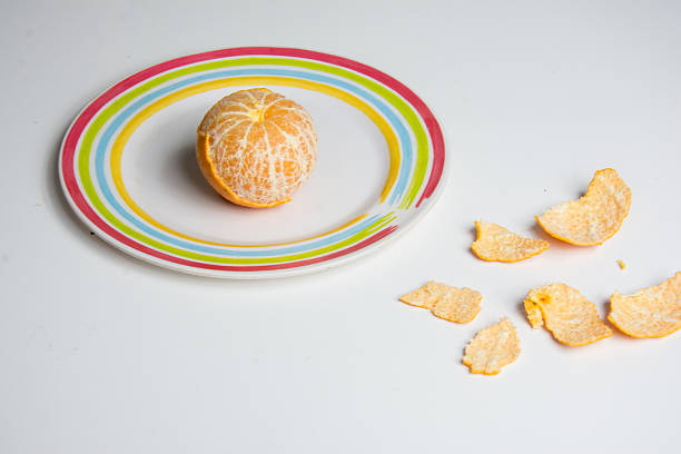 Peeled tangerine on a plate on a white background.