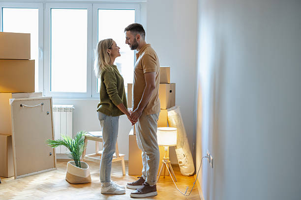 istock Couple holding hands in their new home with moving boxes around 2231142367