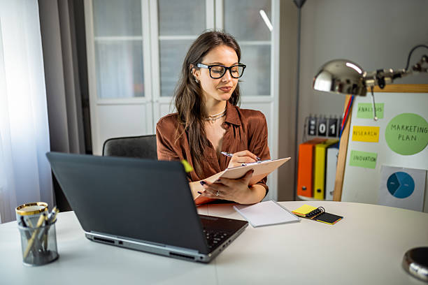 istock Young Woman on Video Call Showing Notes While Working from Home 2231145086