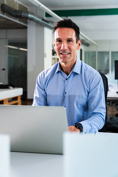 istock Businessman smiling and working on laptop in modern office 2231145116