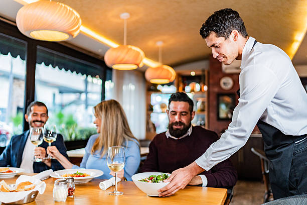 istock Waiter serving food to customers at restaurant 2231146291