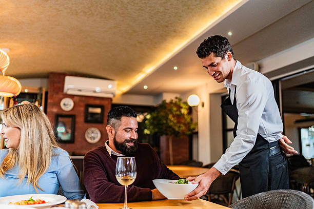 istock Waiter serving food to customers at restaurant 2231146301