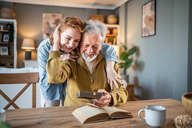 istock Happy senior man reading book with daughter at home 2231146872