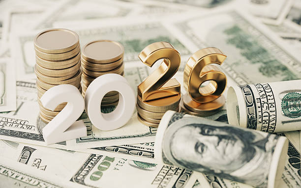 Gold Colored 2026 text and stack coin over 100 American Dollar Bills