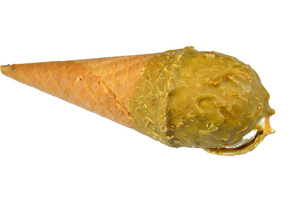 Vibrant and tempting pistachio ice cream cone with crushed nuts on a pink background, creating a refreshing and delicious treat. The image is well-lit, with vibrant colors that enhance its appeal.