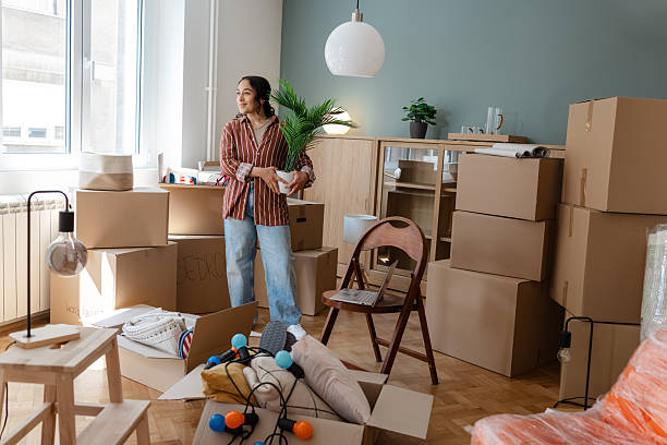 istock Young woman unpacking boxes in her new home during the moving process 2231151124