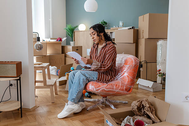 istock Young woman reading documents in her new home surrounded by moving boxes 2231151130